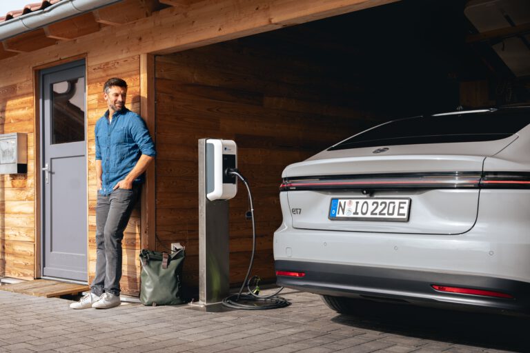 Ein Mann lehnt an einem Carport in dem sein Elektroauto aufgeladen wir - Chris Gollhofer Lifestyle Fotografie - Bayern