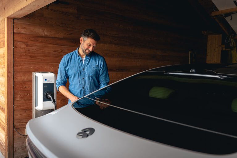 Ein Mann steht in einem Carport während sein Auto aufgeladen wird - Chris Gollhofer - Lifestylefotografie - Österreich