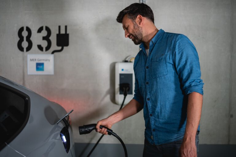 Aufnahme eines Mannes der in einer Tiefgarage gerade den Ladestecker in sein Elektroauto steckt - Chris Gollhofer Lifestyle Fotograf - München