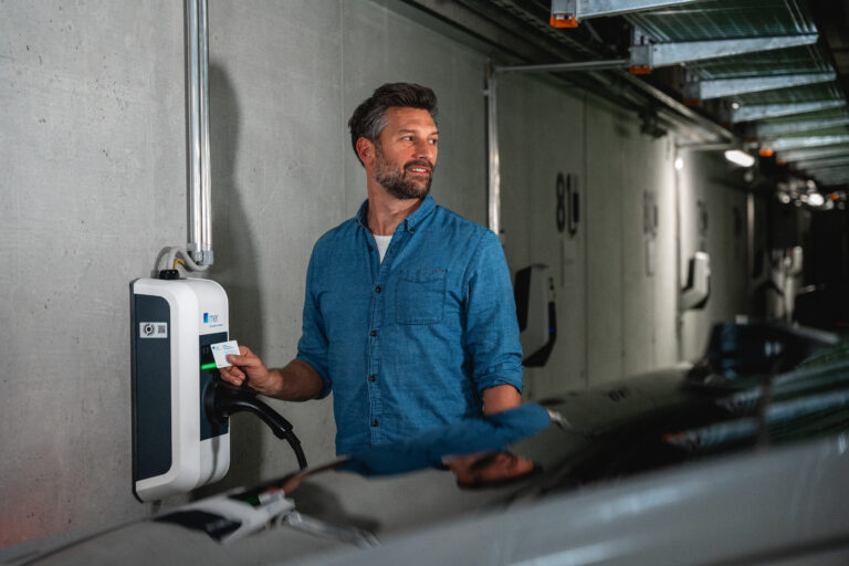 Ein Mann hält eine Chipkarte an die Wallbox in einer Tiefgarage - Chris Gollhofer Lifestylefotograf - München